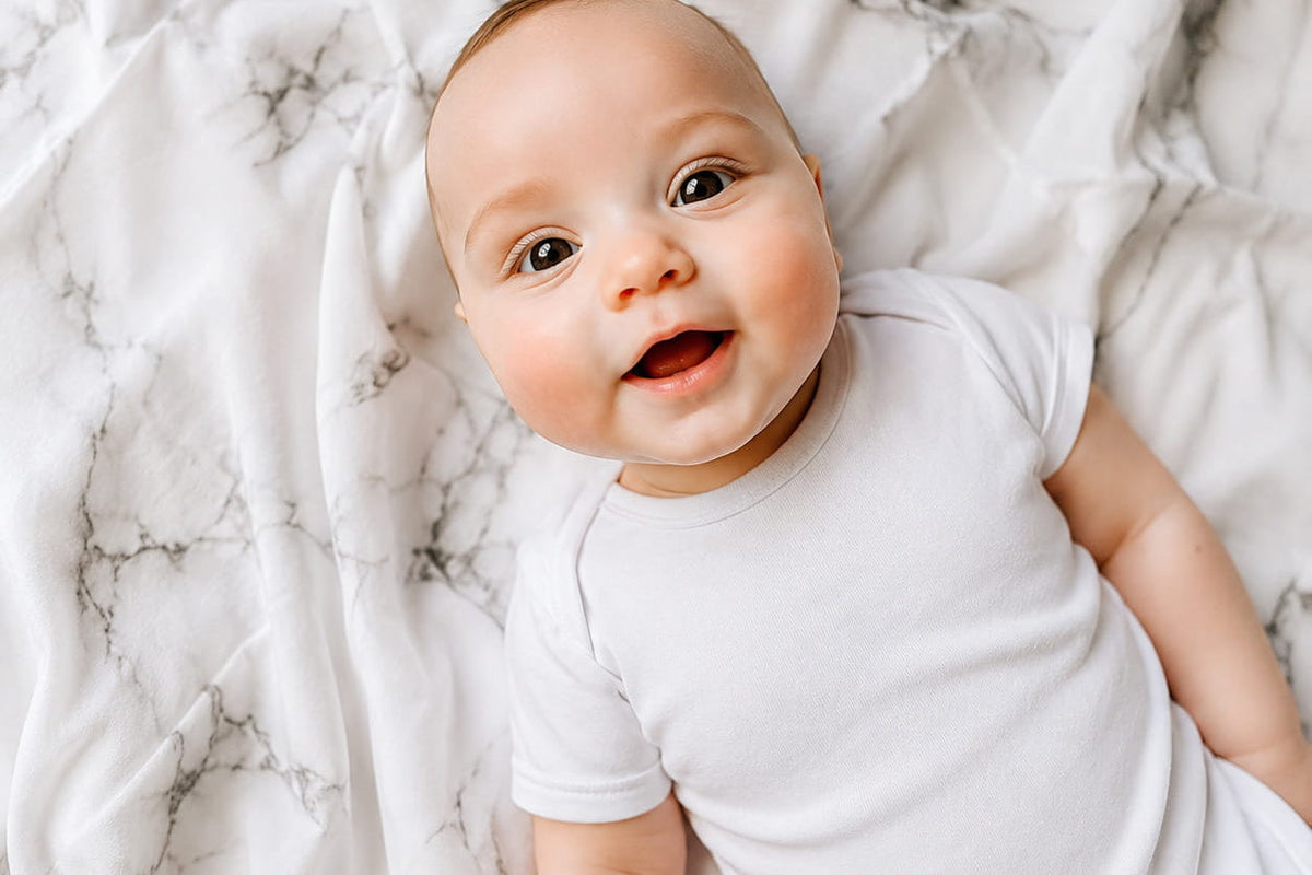 Kraamcadeau ideeën: blije baby op MIMMTI hydrofiele doeken
