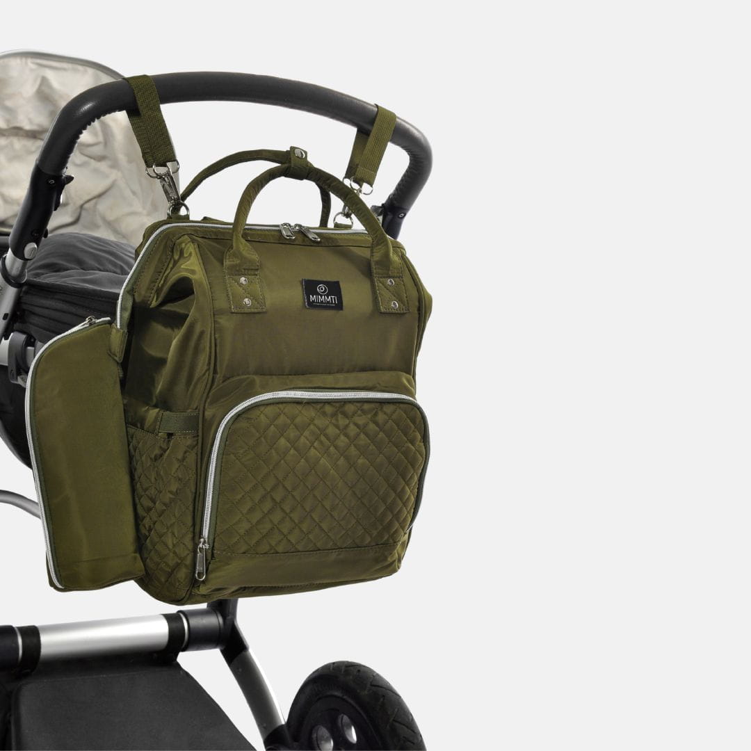 Olijfgroene MIMMTI 1.0 luiertas rugzak onderweg met baby