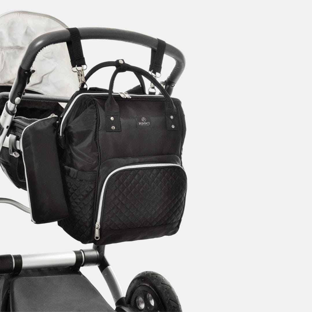 Ouder onderweg met baby en zwarte MIMMTI 1.0 luiertas rugzak