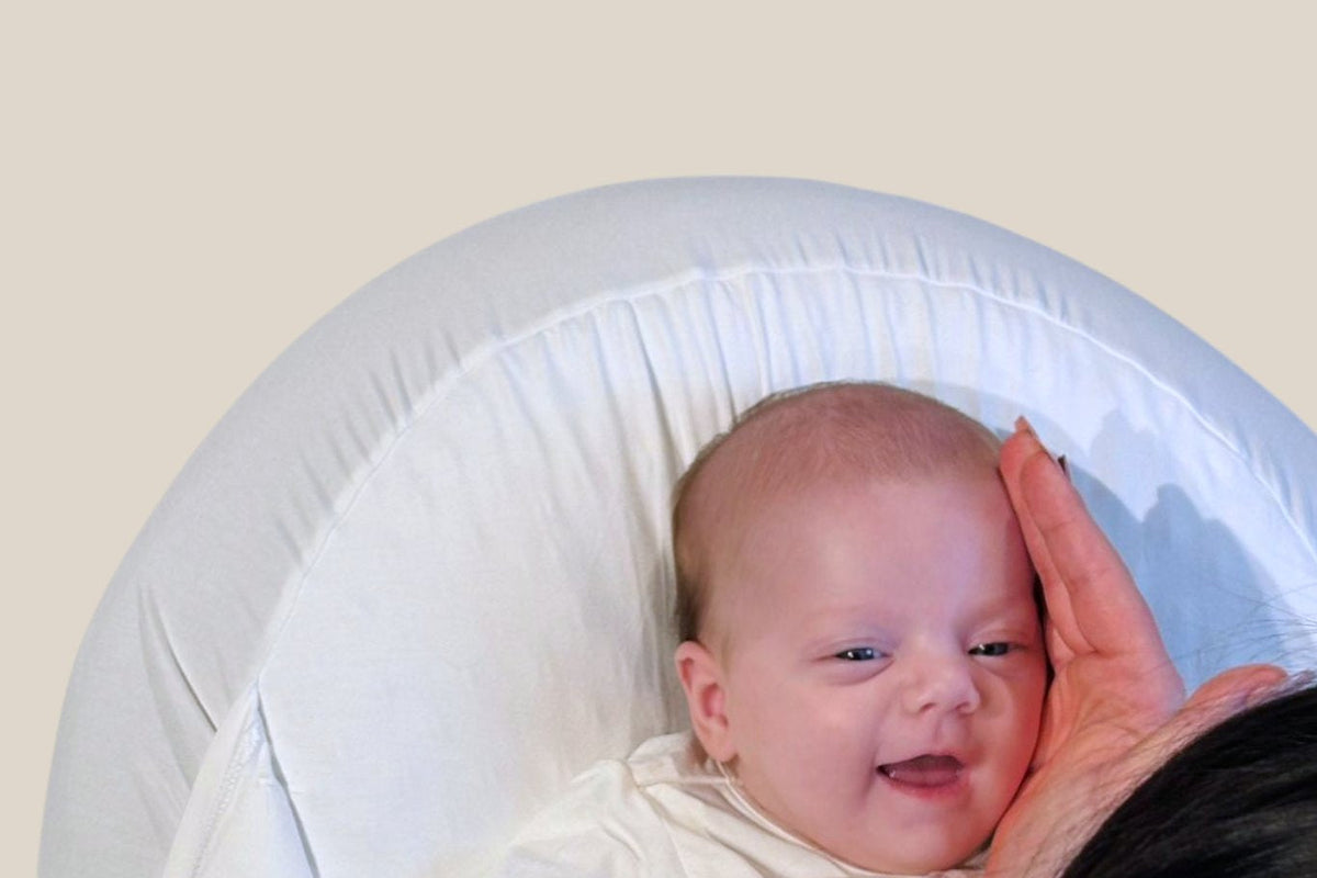 Relaxhoes voedingskussen: lachende baby in de MIMMTI Sleepynest