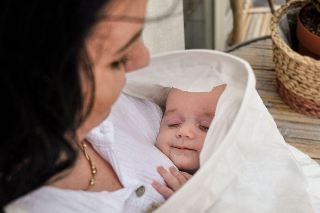 Borstvoeding houdingen: baby kijkt omhoog tijdens het voeden onder de voedingsdoek
