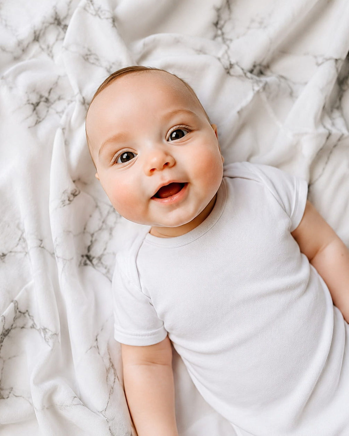 Lachende baby op MIMMTI hydrofiele doek met marmerprint van katoen