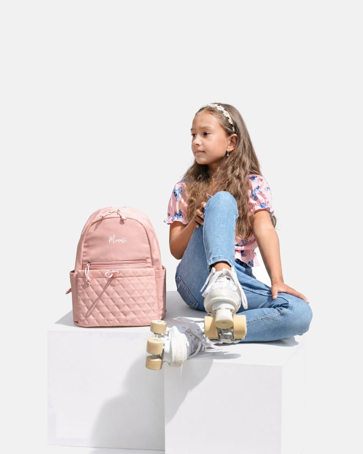 Kind op rolschaatsen naast de MIMMTI Mini luiertas in dusty roze