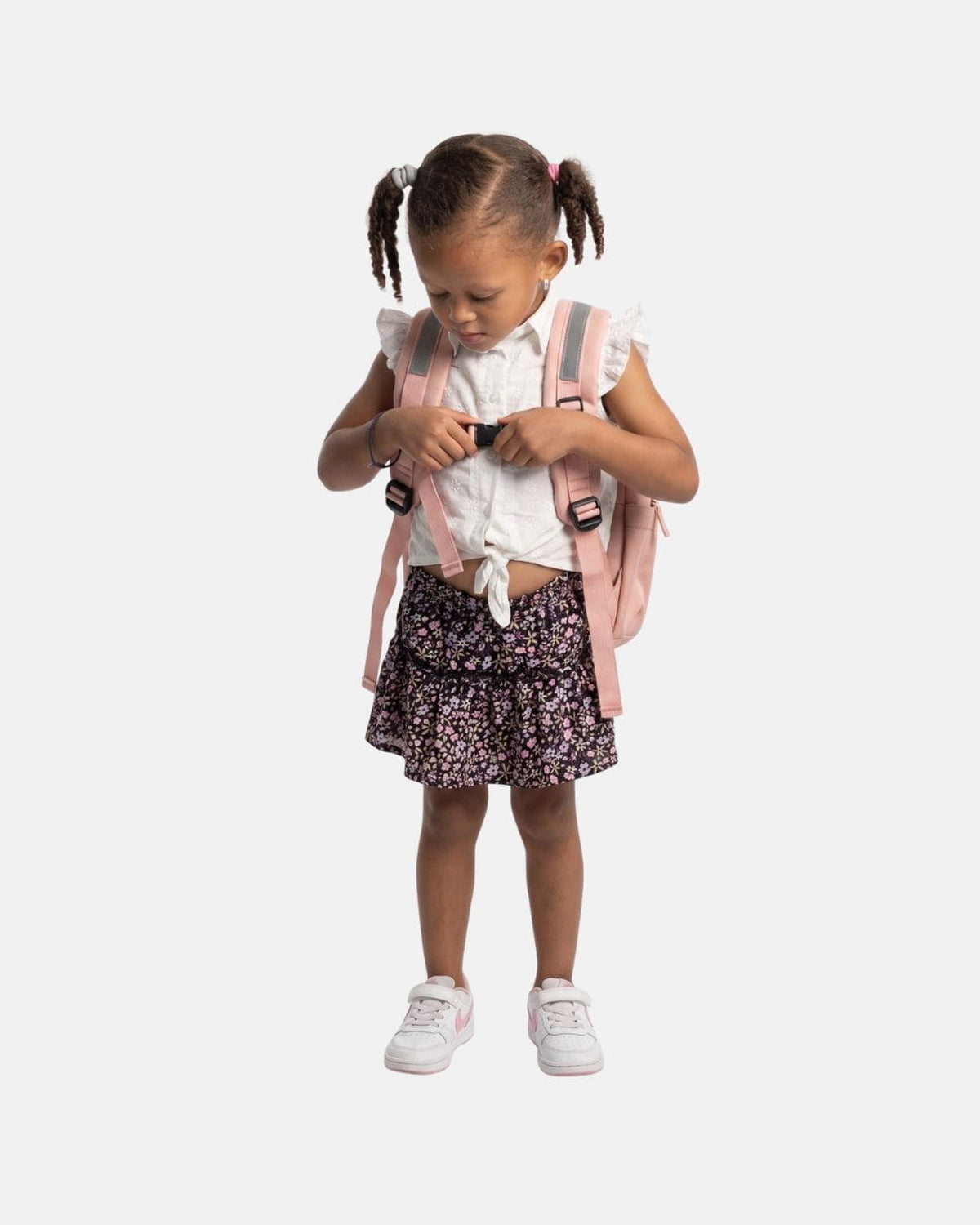Kind sluit de borstband van de MIMMTI Mini luiertas in dusty roze
