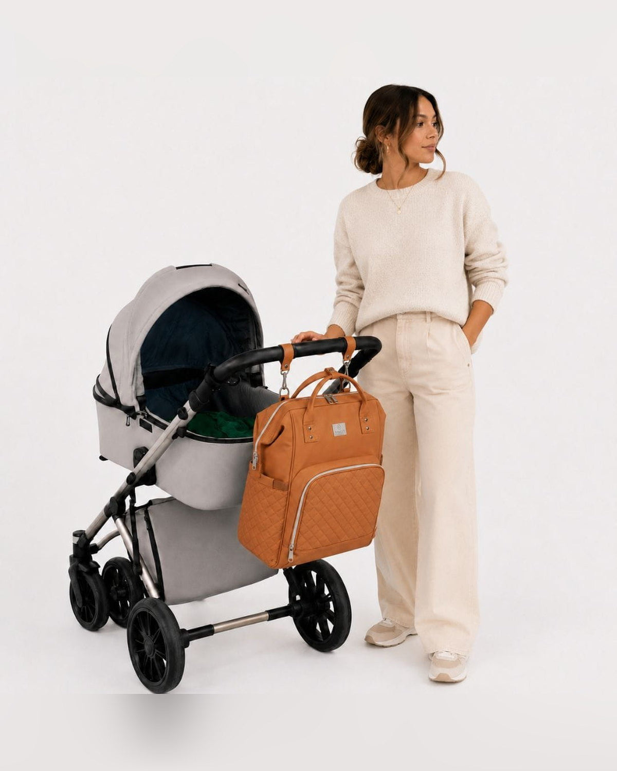 Vrouw met kinderwagen, MIMMTI 2.0 luiertas rugzak in cognac aan de duwstang