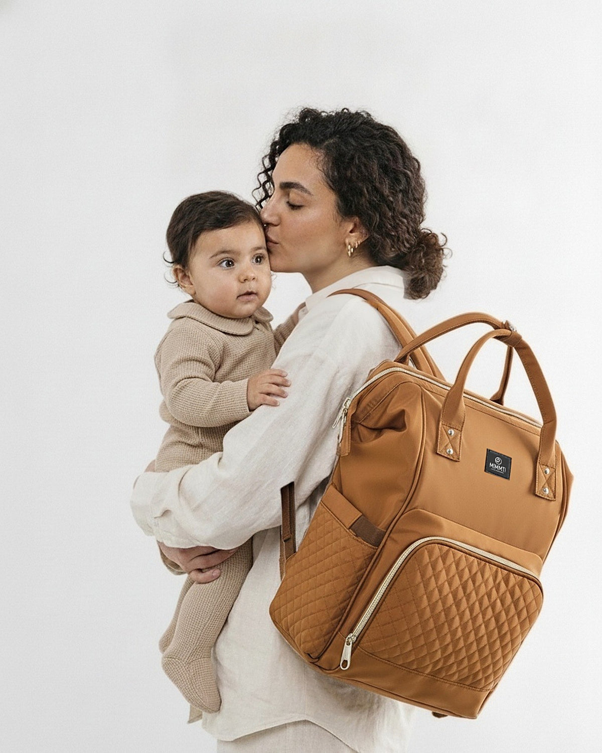 Moeder met baby op de arm, MIMMTI 1.0 luiertas rugzak in cognac