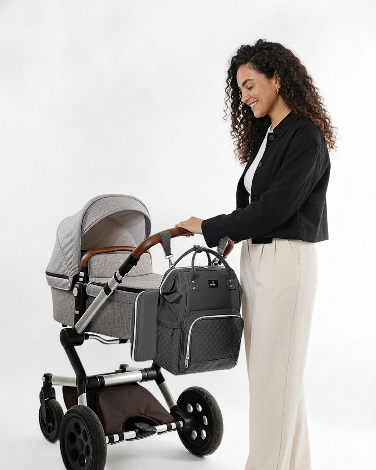 Moeder bij de kinderwagen met de MIMMTI 1.0 luiertas rugzak in grijs