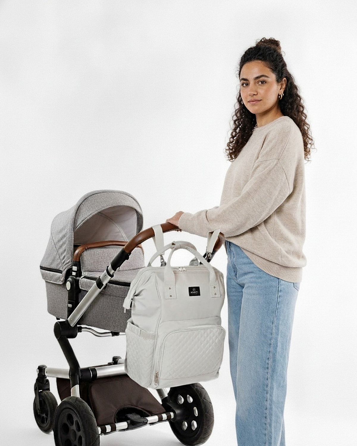 Moeder bij de kinderwagen met de MIMMTI 1.0 luiertas rugzak in lichtgrijs