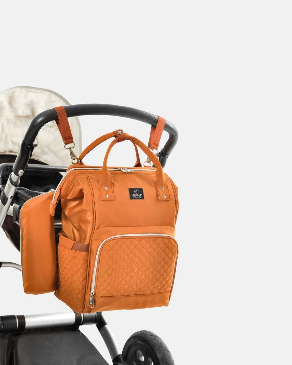 Cognac · MIMMTI 1.0 luiertas rugzak in cognac aan de kinderwagen met kinderwagenclips
