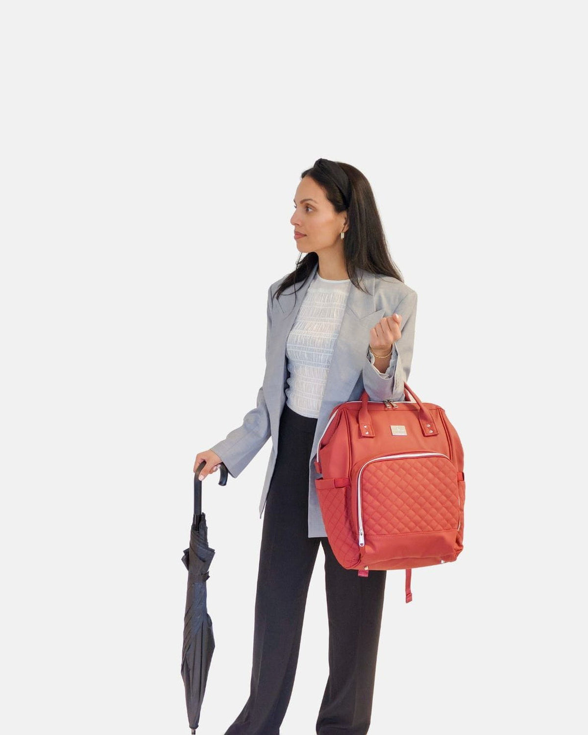 Vrouw met paraplu draagt de MIMMTI 2.0 luiertas rugzak in cherry in de hand