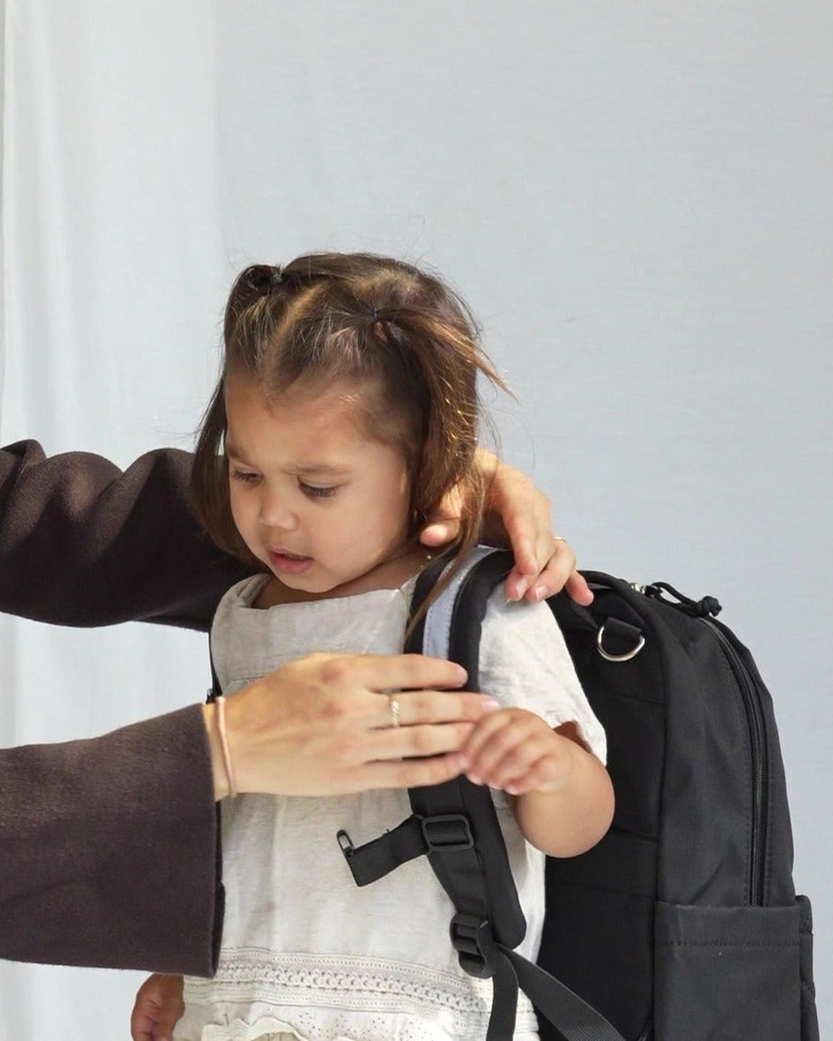 Kind krijgt de MIMMTI Kids Bag kinderrugzak in zwart om, borstriem en schouderbanden