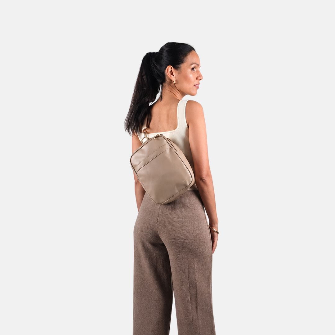 Vrouw draagt de MIMMTI Zoya luiertas in sand crossbody op de rug