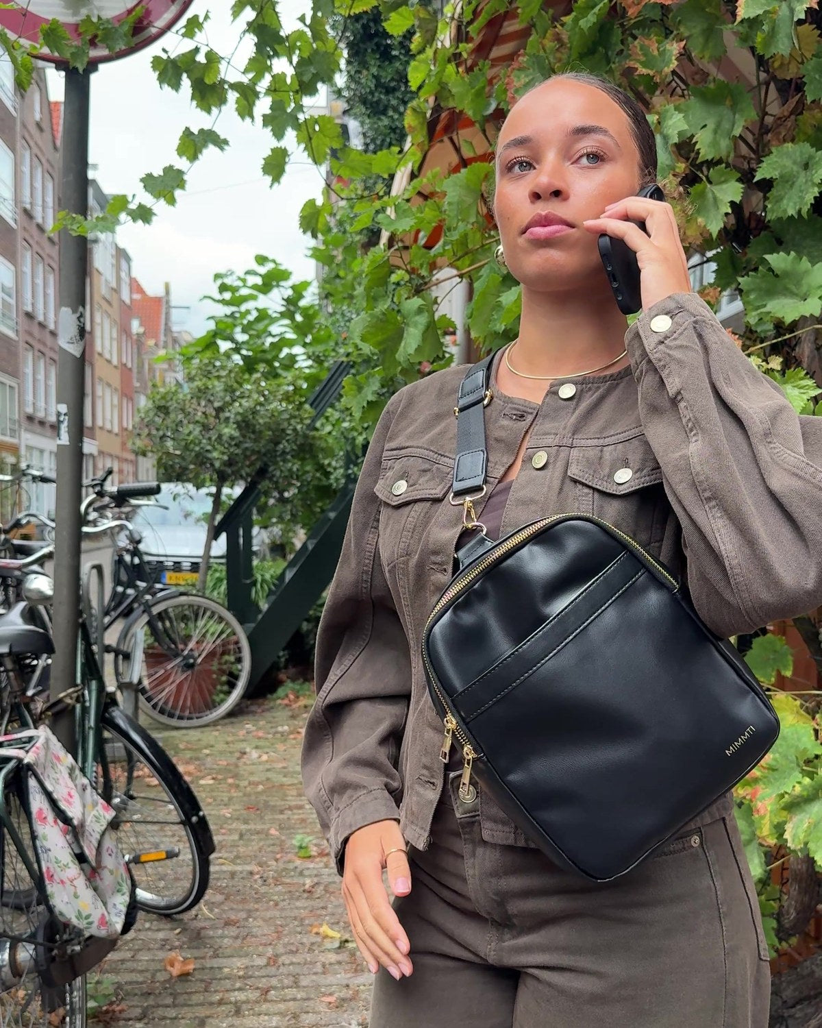 Vrouw draagt de MIMMTI Zoya luiertas in zwart crossbody in de stad