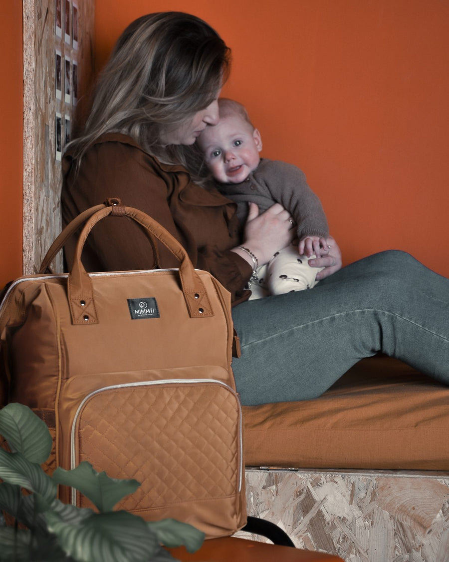 Mother with her baby and the MIMMTI 1.0 diaper bag backpack in Cognac